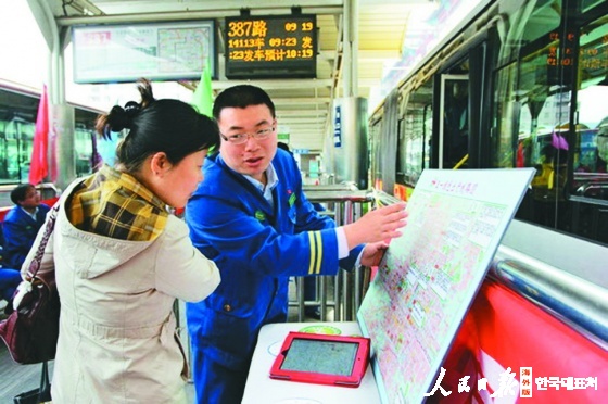장체밍이 승객에게 교통선로도표를 설명하고있다. 图为张鹊鸣向乘客指引公交出行线路