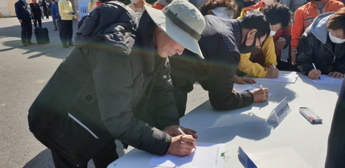 ▲ 서명지에 서명하는 곽길성 전 농민회장 "석탄재가 아닌 진도토사를 활용한 진도항 배후지 개발사업에 적극 찬성한다"